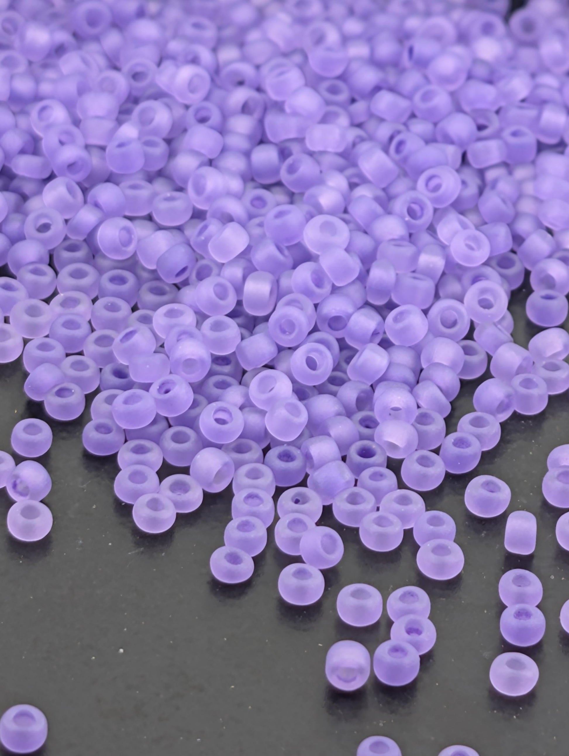 a close-up view of numerous small, round, purple beads scattered across a dark surface.