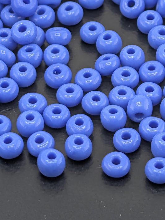 a collection of small, round, blue beads scattered on a dark surface.