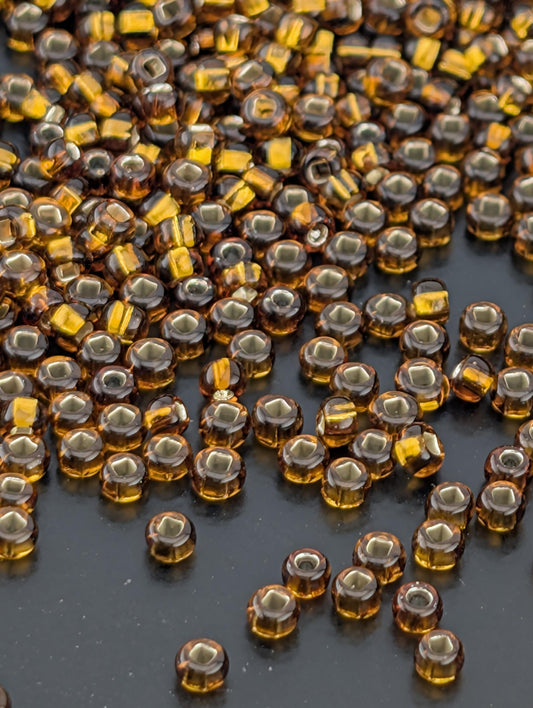 a close-up view of numerous small, round, brown glass beads scattered across a dark surface.