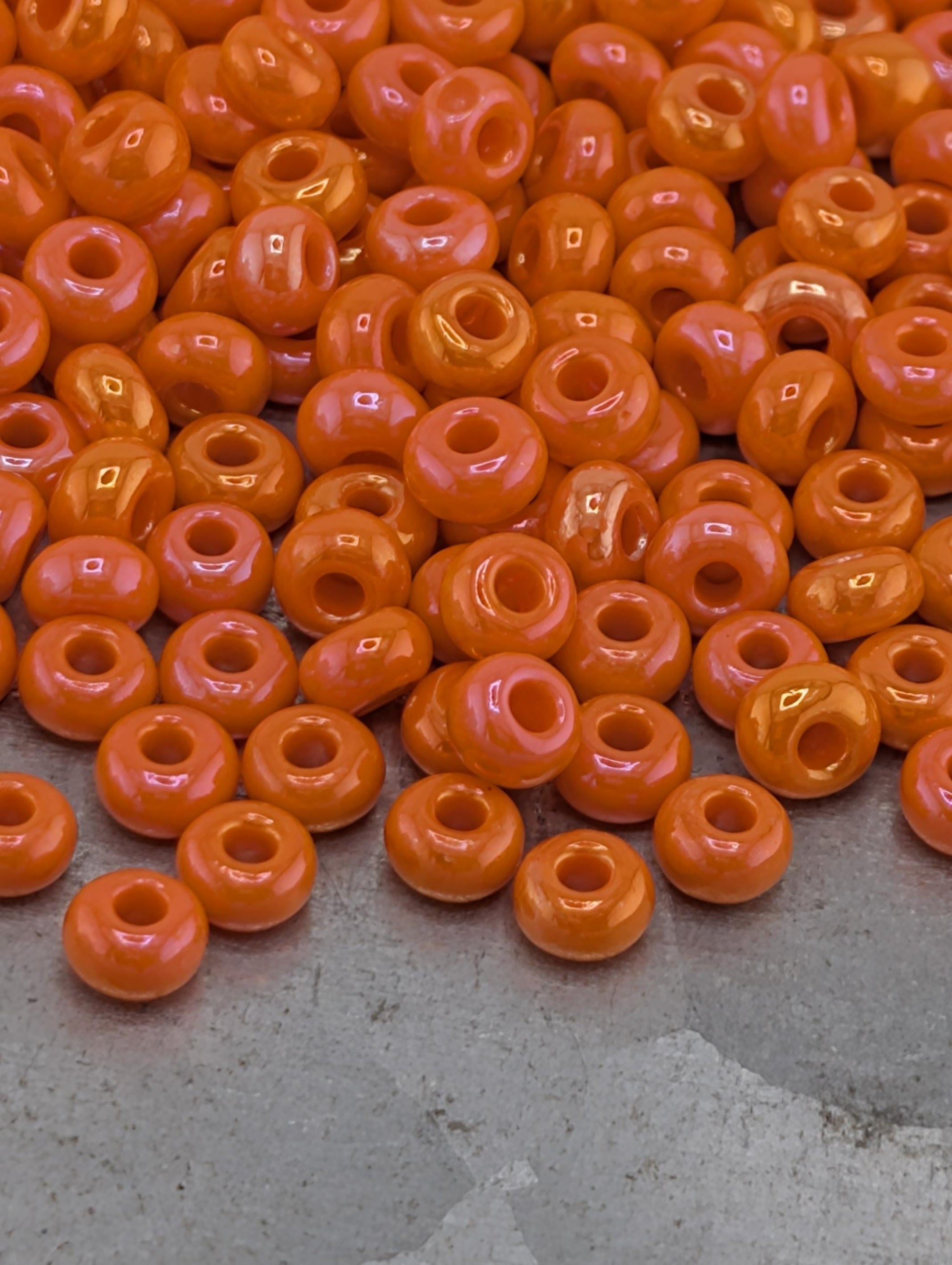 a large pile of orange beads scattered on a gray surface.