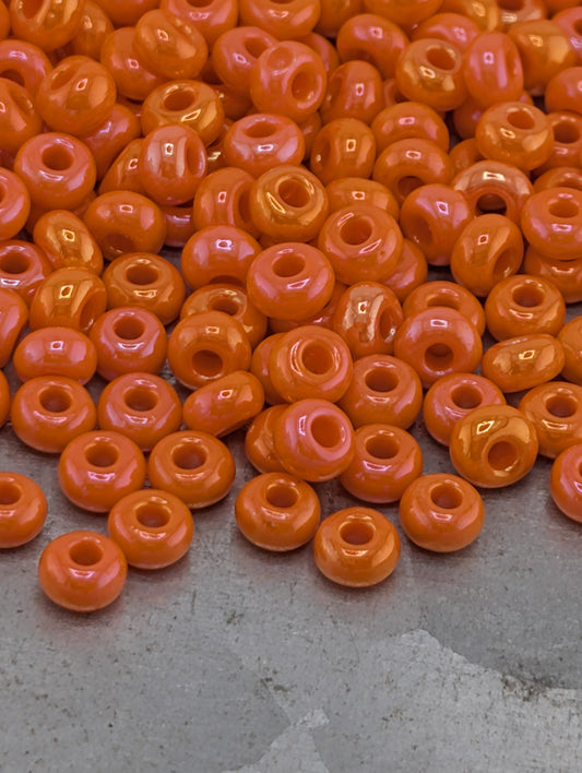 a large pile of orange beads scattered on a gray surface.