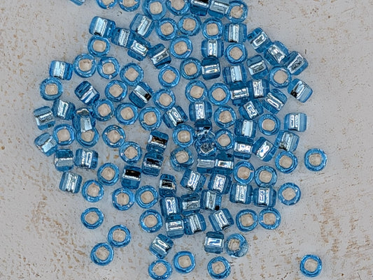 5140SB Silver Lined Translucent Light Aqua Round With Square Hole 6/0 (15g Pkg)