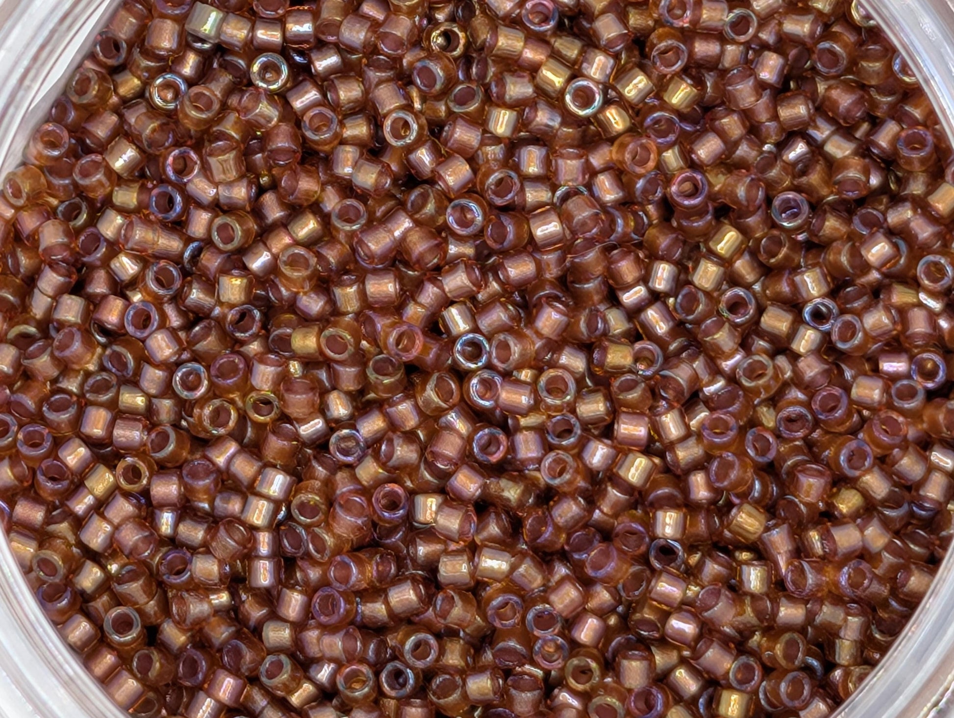 A close-up image of a large pile of small, round beads in various shades of brown.