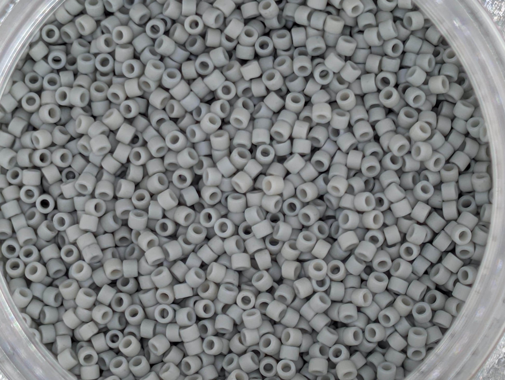 A close-up image of a container filled with small, white beads or plastic beads.