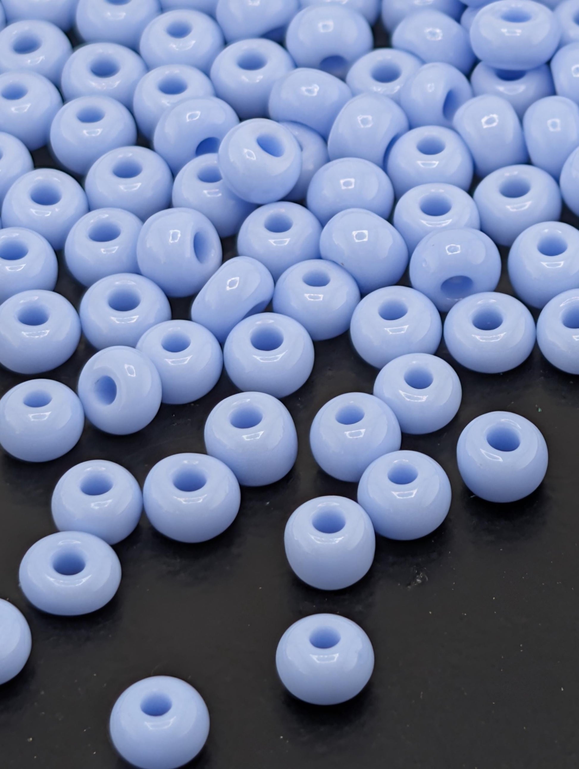 a collection of small, round, blue beads scattered on a dark surface.
