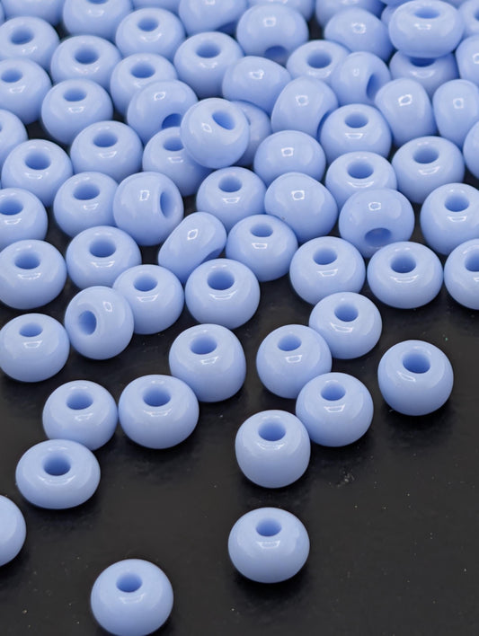 a collection of small, round, blue beads scattered on a dark surface.