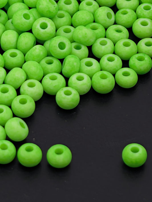 a collection of neon green beads scattered on a dark background.