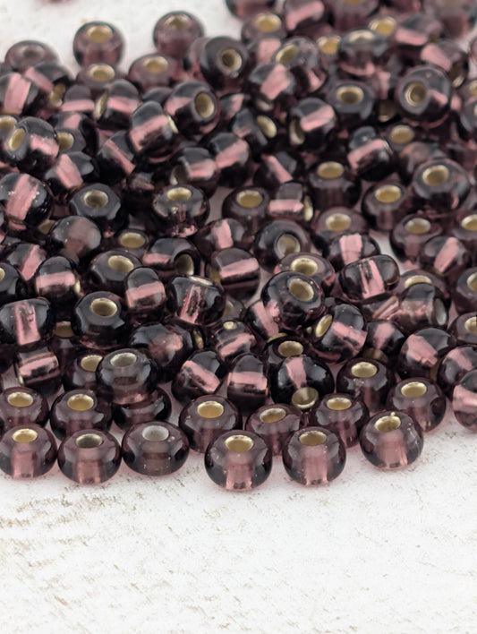 a large pile of purple and black beads scattered on a white surface.