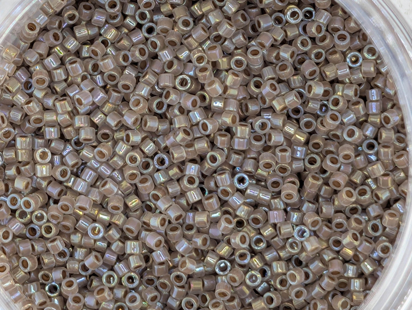 A close-up image of a container filled with numerous small, round beads in various shades of brown.