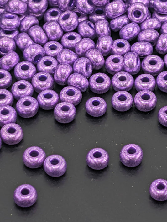 a collection of purple beads scattered on a dark surface, with some of the beads overlapping each other.