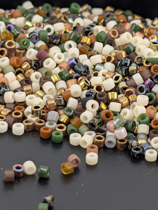 A pile of multicolored beads, including white, green, orange, and brown, scattered on a dark surface.