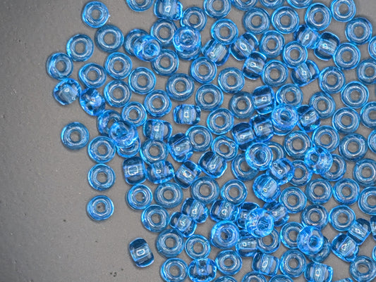 a collection of small, clear blue beads scattered across a gray surface.