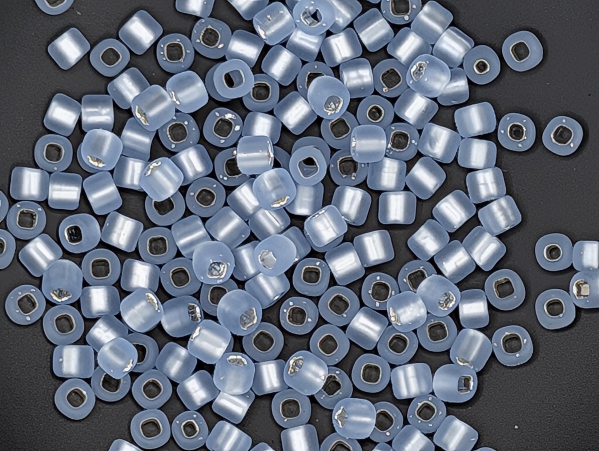 a collection of small, clear beads scattered on a dark background.