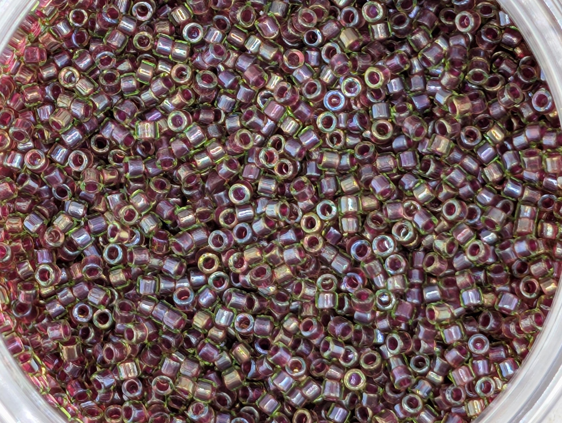 A close-up image of a large pile of small, round beads in various shades of purple and green.