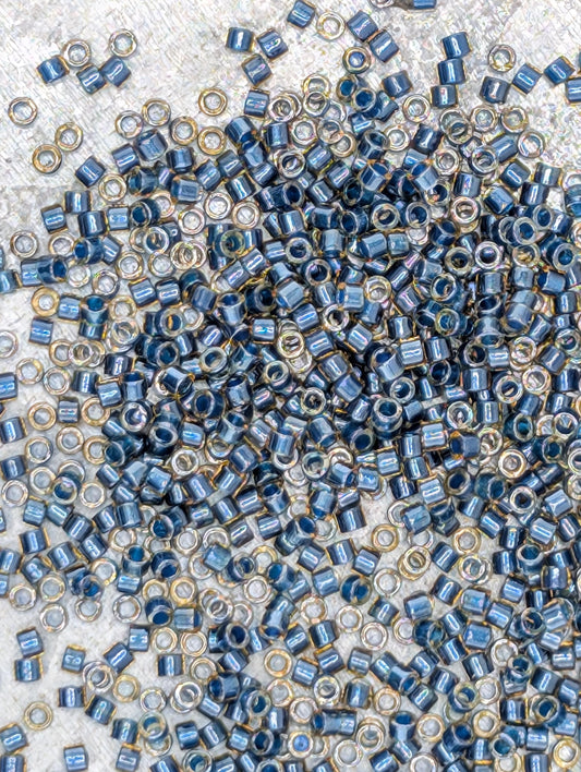 The image is a close-up of numerous small blue and gold beads scattered across a surface.