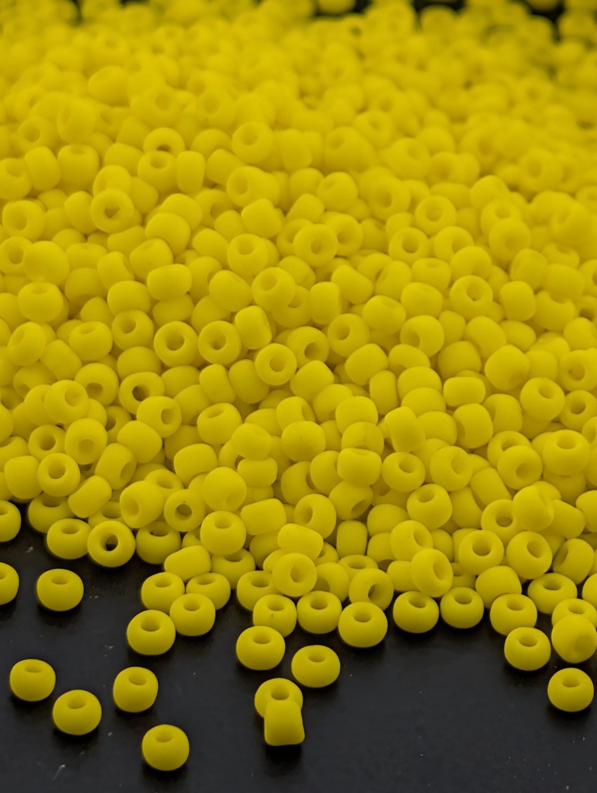 A large pile of yellow beads or beads scattered on a dark surface.
