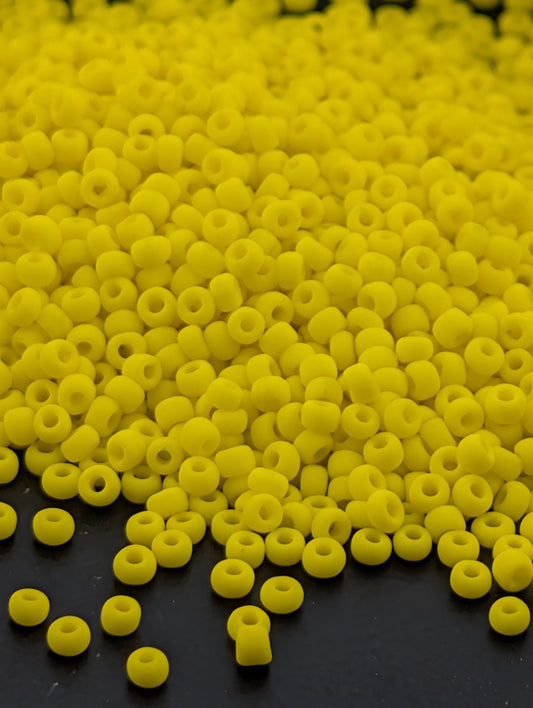 A large pile of yellow beads or beads scattered on a dark surface.