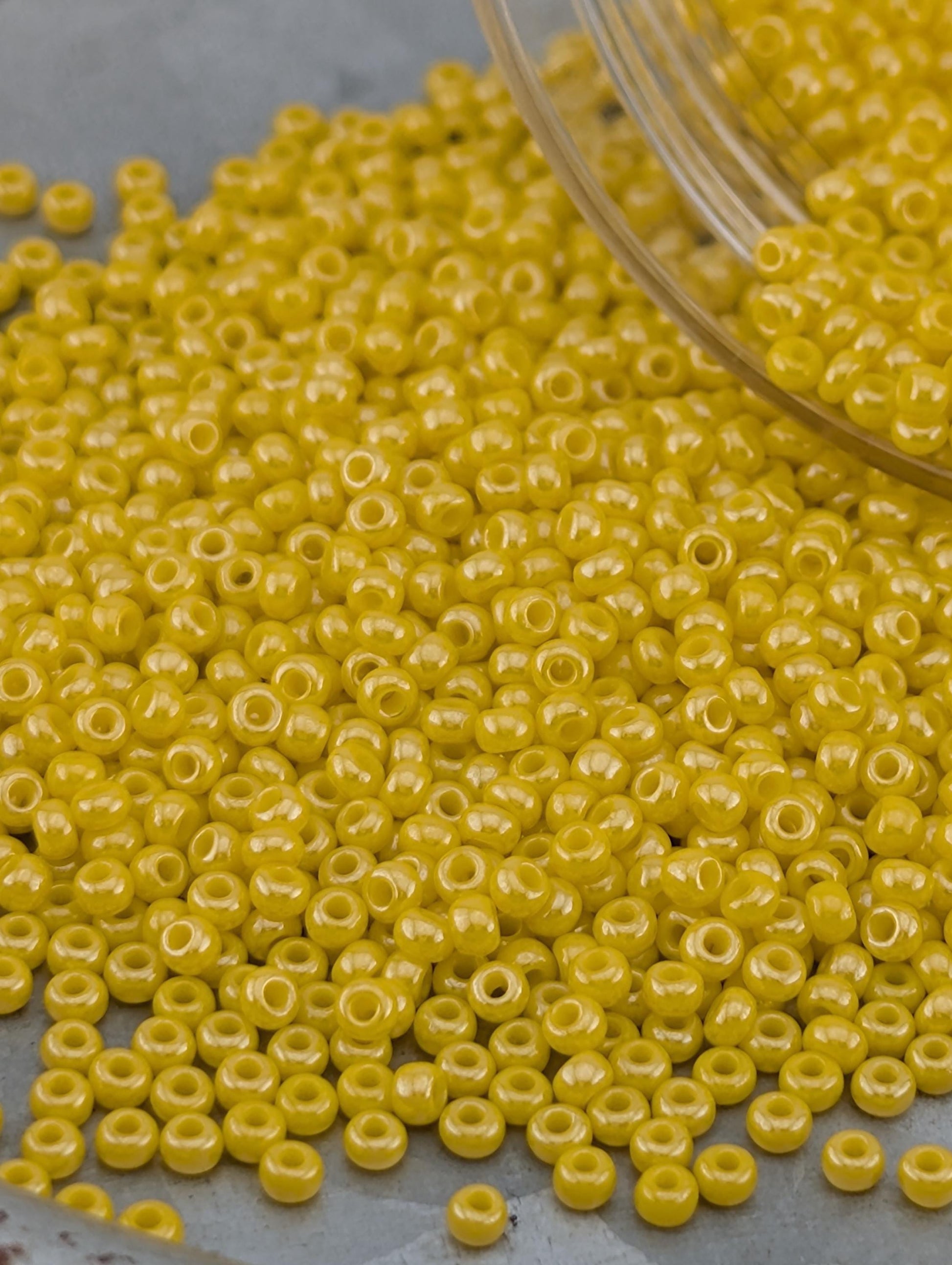 A pile of yellow beads on a gray surface.