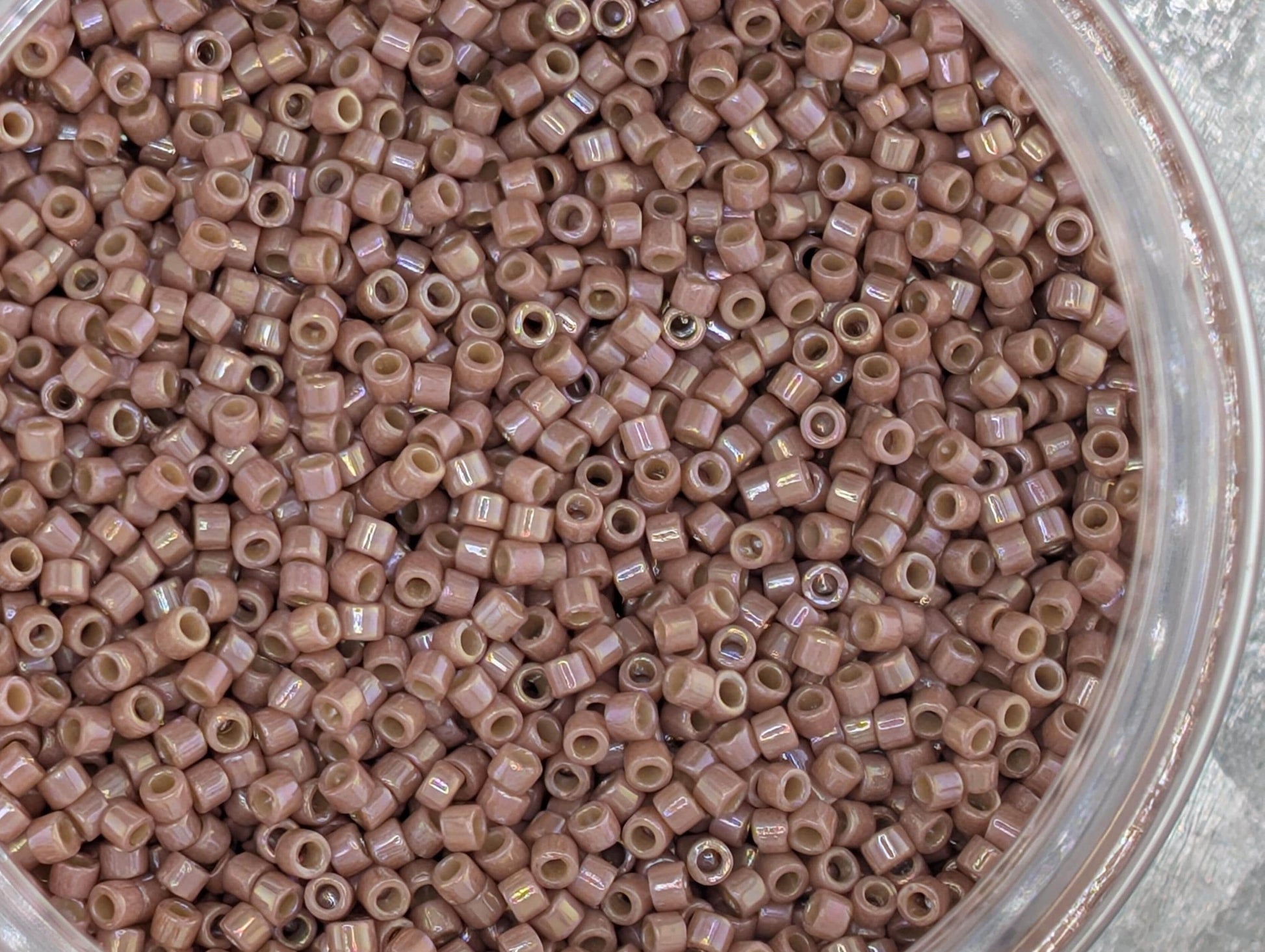 A close-up image of a container filled with numerous small, round beads in a light brown color.