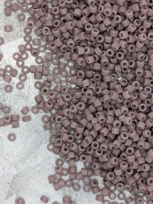 a large pile of small, round beads in various shades of pink, scattered across a surface.