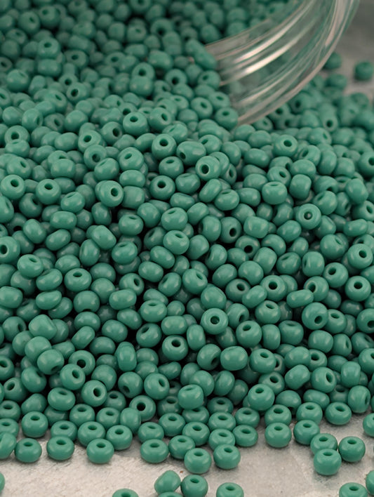 A large pile of green beads spilling out of a transparent container.
