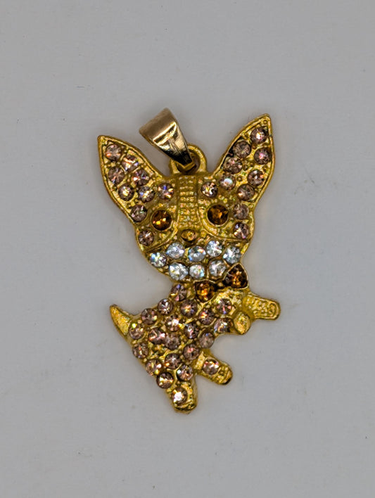 A gold-colored pendant or charm with a detailed design, featuring a combination of gold, diamonds, and other embellishments.
