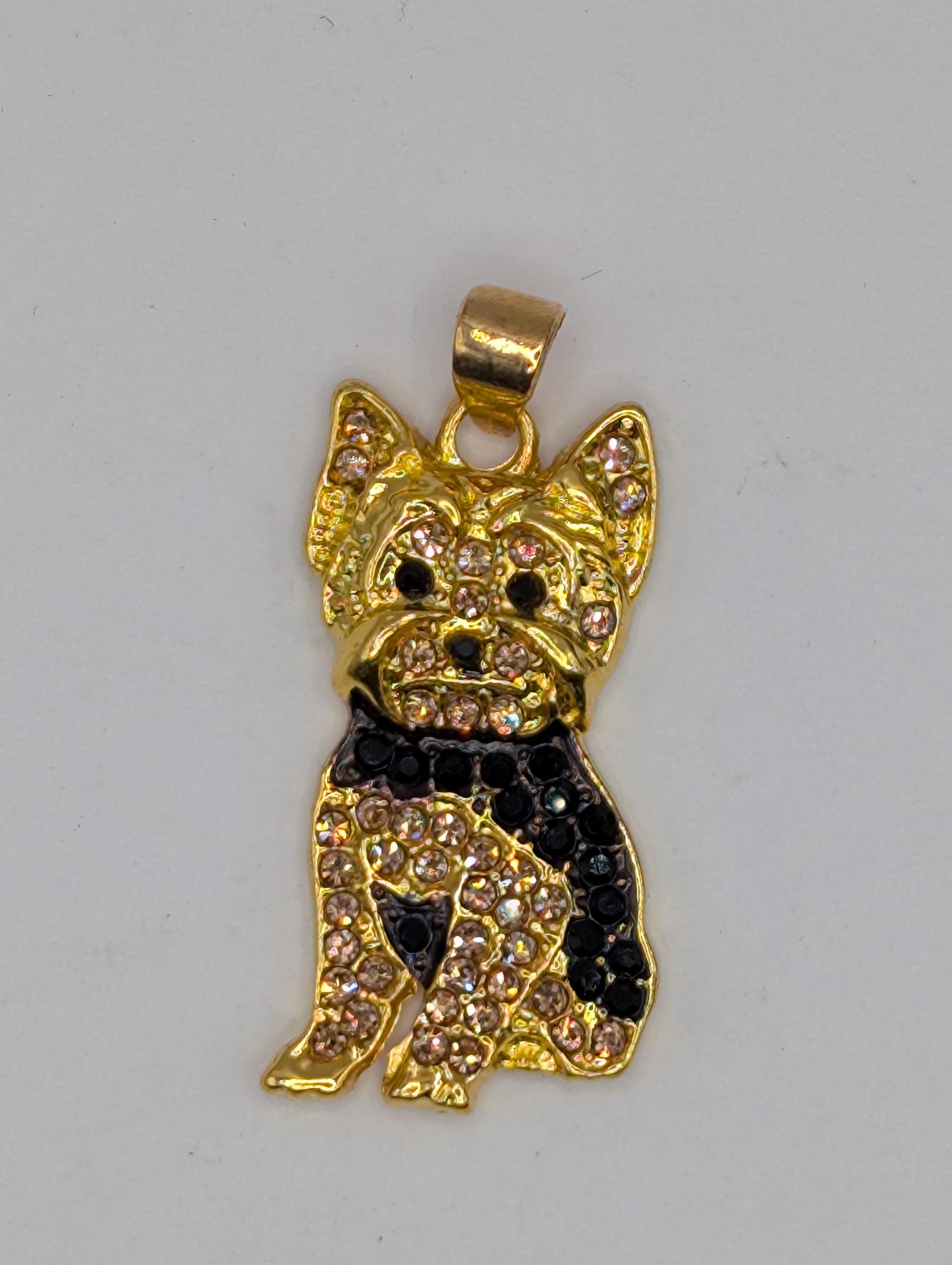 A gold-colored pendant in the shape of a dog, adorned with small diamonds and rhinestones.