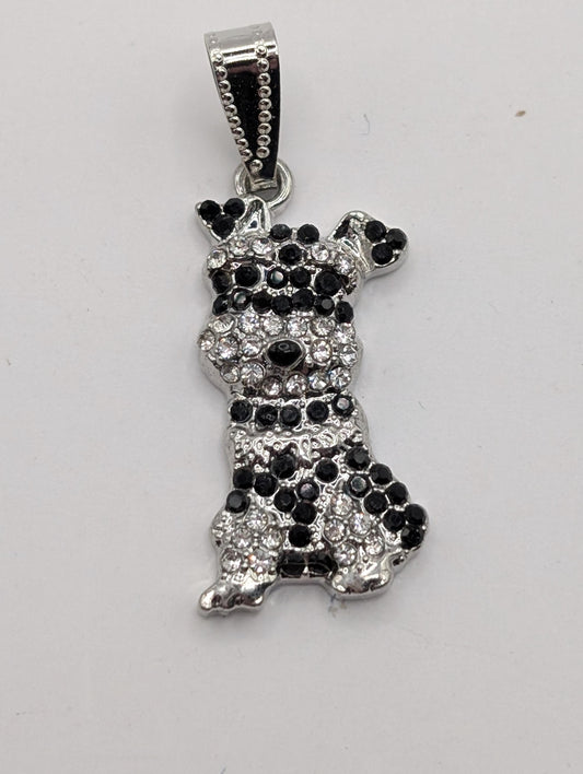 A silver-toned pendant in the shape of a dog, adorned with black and white rhinestones or crystals.