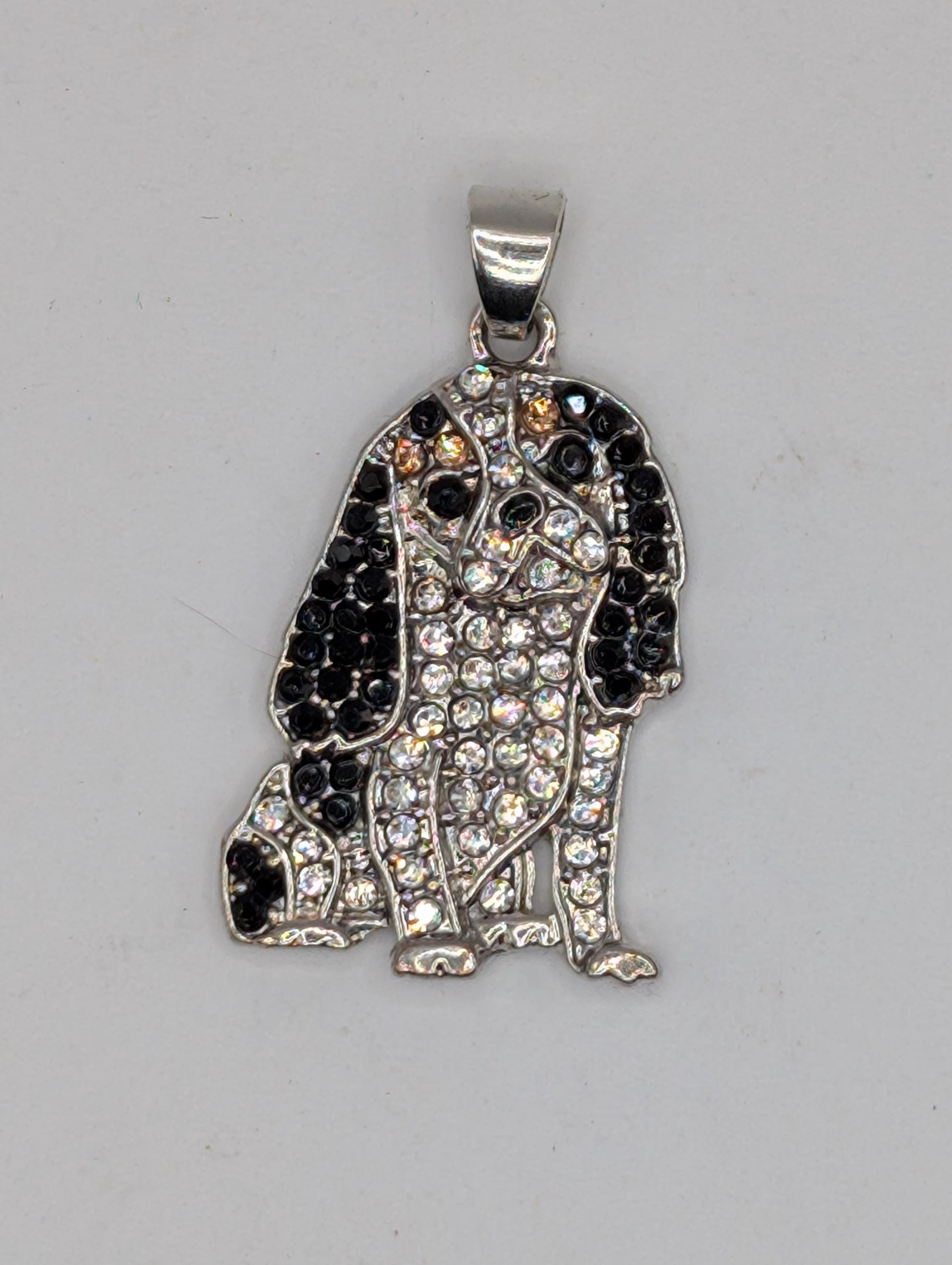 A silver-colored pendant or charm with a black and white design, featuring a combination of small black and white stones or crystals.