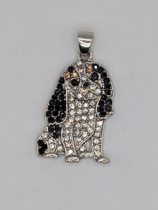 A silver-colored pendant or charm with a black and white design, featuring a combination of small black and white stones or crystals.
