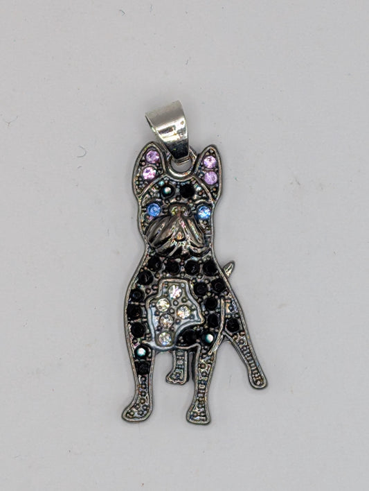 A silver-colored pendant in the shape of a dog, adorned with colorful gemstones and sparkling crystals.