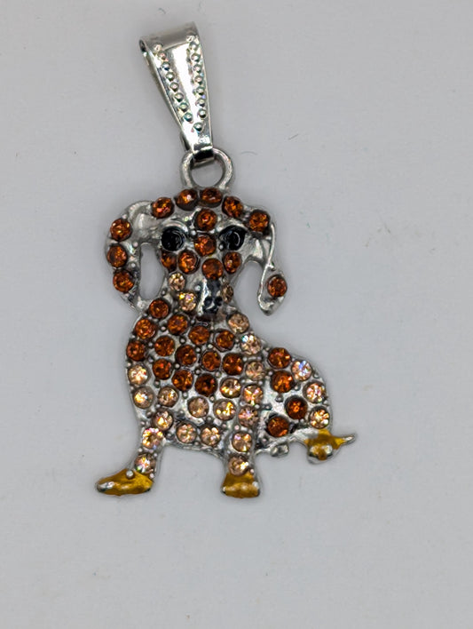A silver-colored pendant in the shape of a dog, adorned with numerous small, multicolored gemstones.