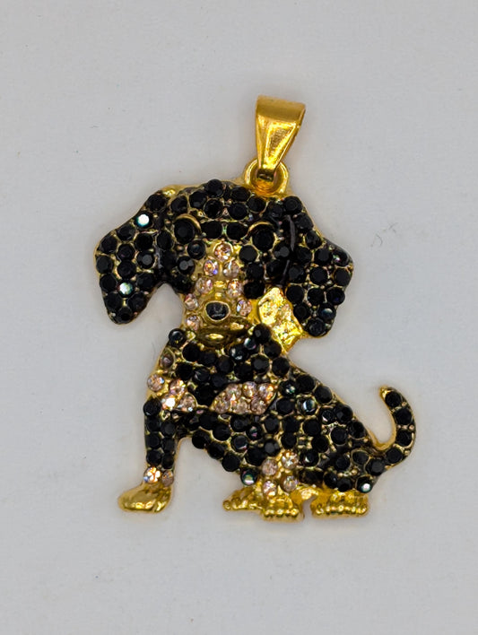 A decorative pendant in the shape of a dog, made of black and gold materials, adorned with numerous small diamonds.