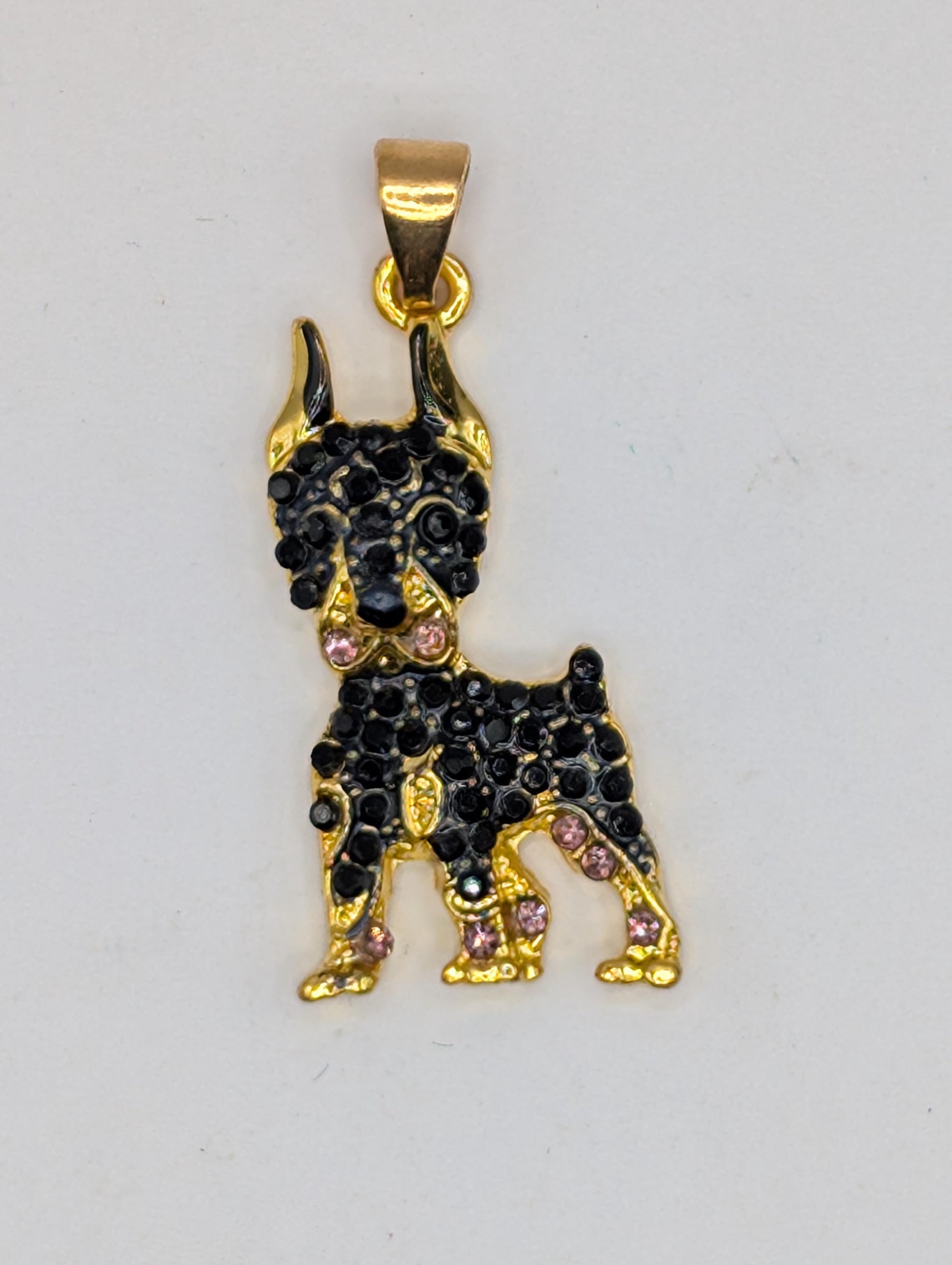 A gold-colored pendant in the shape of a dog, adorned with black gemstones.