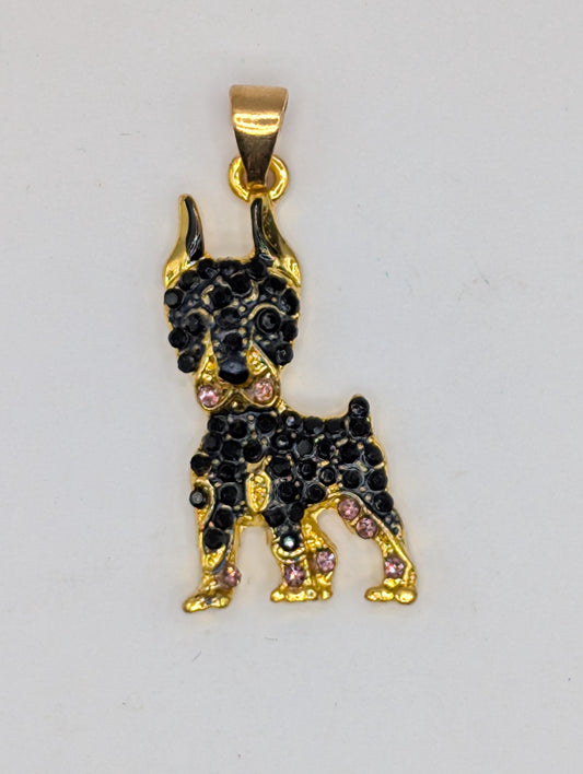 A gold-colored pendant in the shape of a dog, adorned with black gemstones.