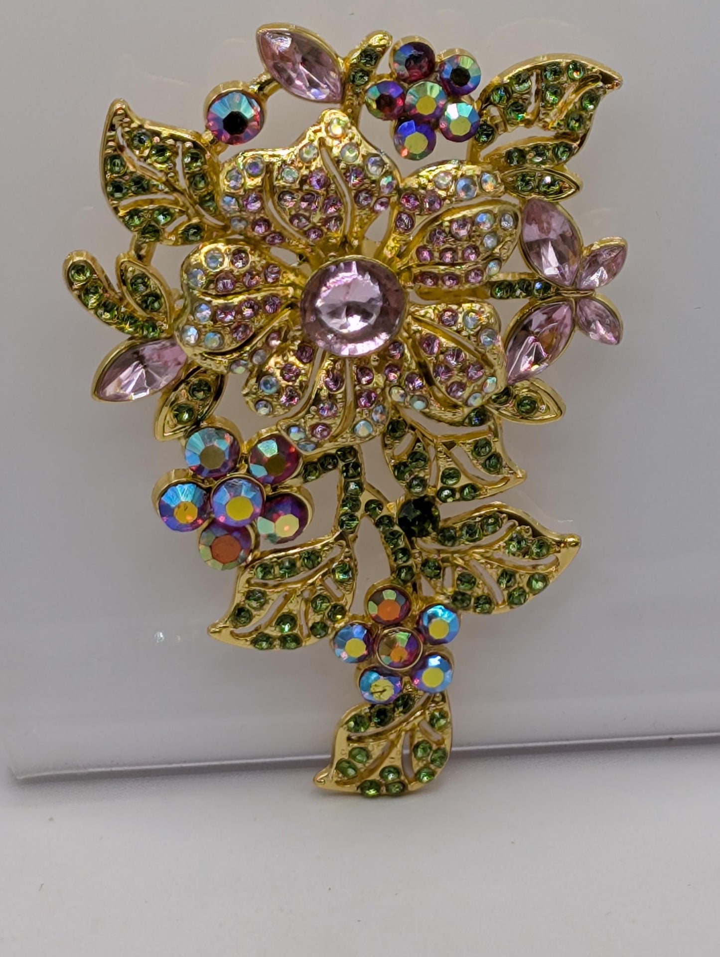 a decorative piece of jewelry with a floral design, adorned with colorful gemstones and leaves.