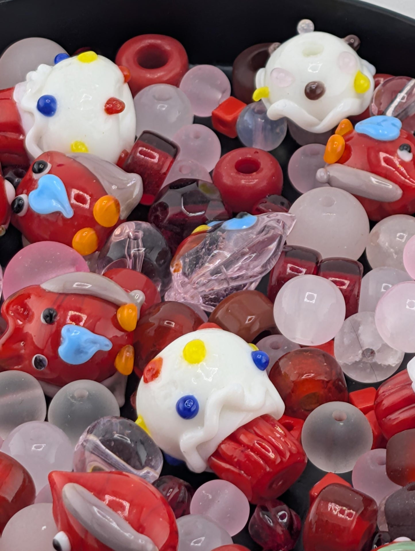 a variety of colorful glass beads and objects, including small glass beads, glass figurines, and glass beads in different shapes and sizes.
