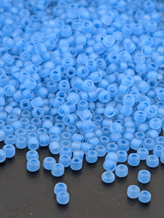 a large pile of small, clear blue beads scattered on a dark surface.