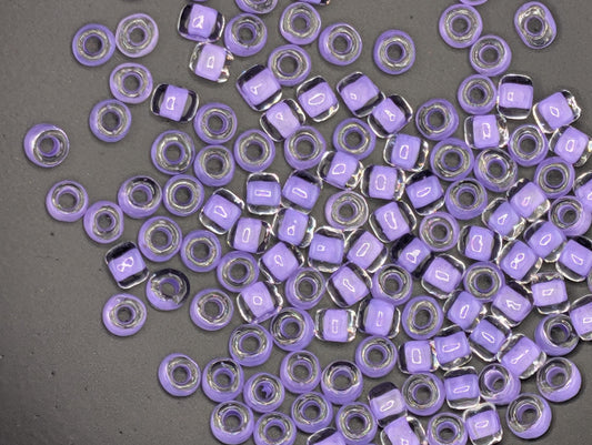 a collection of small, clear beads in various shades of purple scattered across a gray surface.