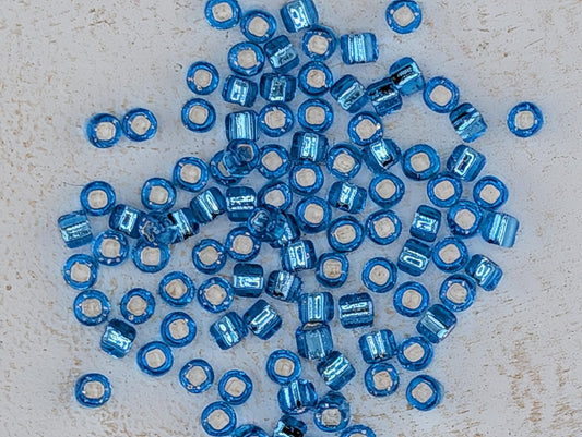 5137SB Silver Lined Translucent Aqua Round With Square Hole 6/0 (15g Pkg)