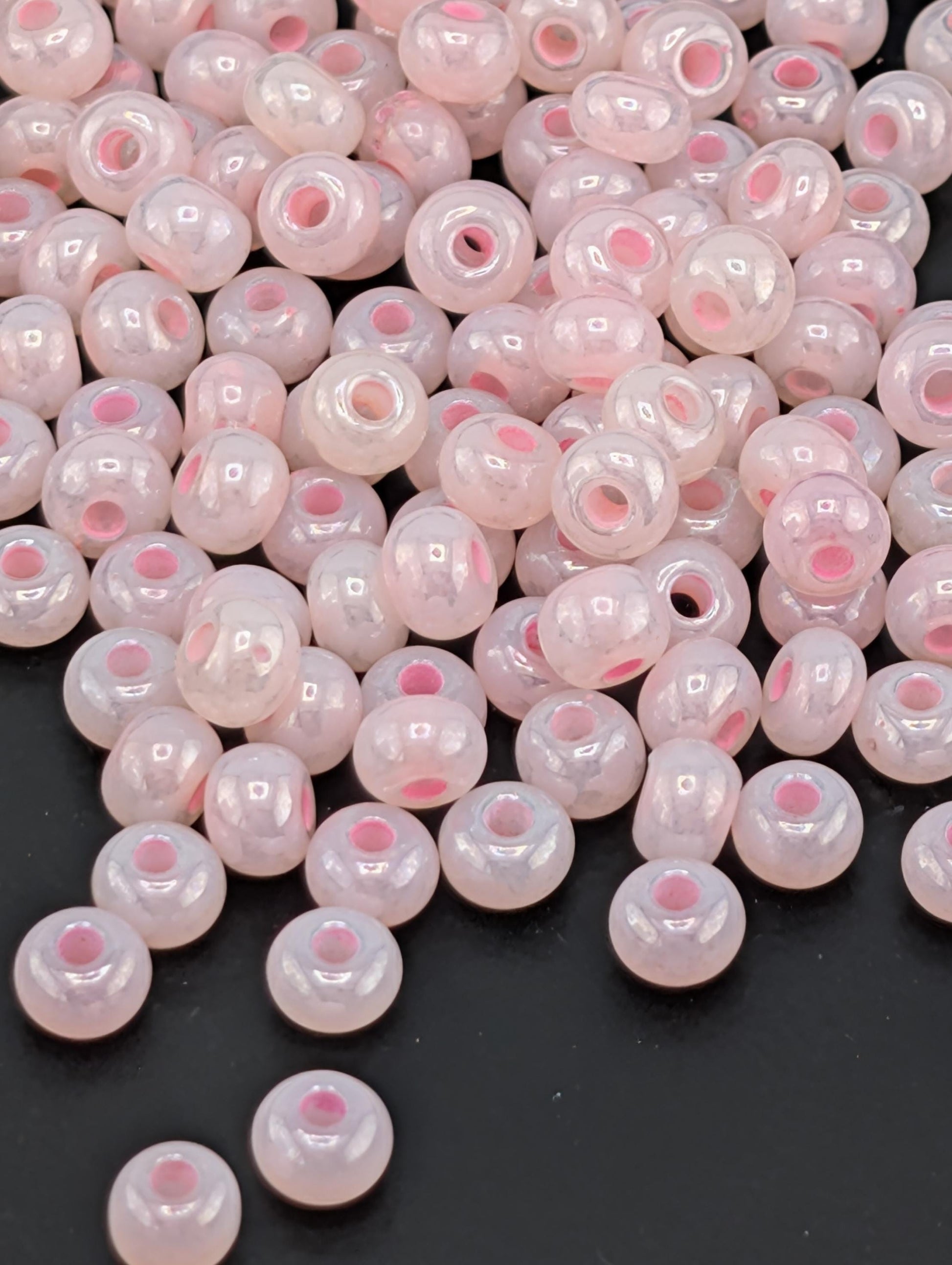 a collection of small, round beads in shades of pink and white, scattered on a dark background.