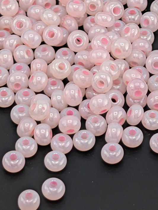 a collection of small, round beads in shades of pink and white, scattered on a dark background.