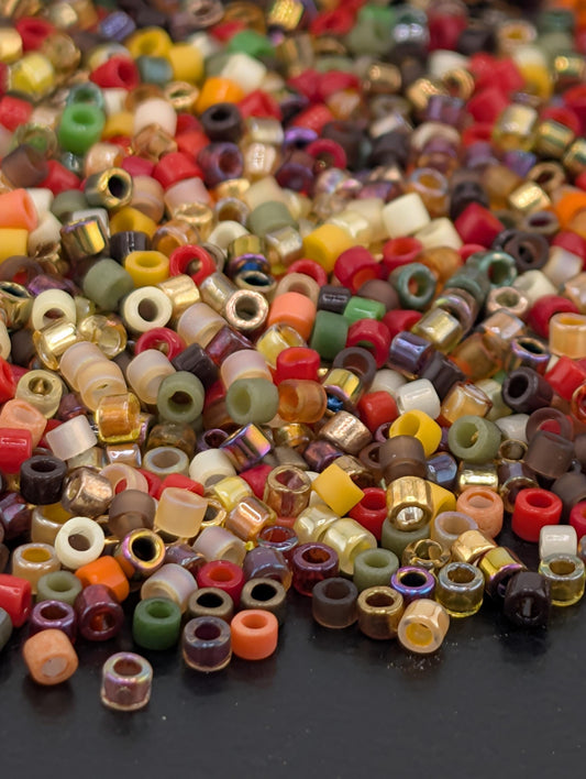 A colorful assortment of multicolored beads, including various shapes and sizes, scattered on a dark surface.