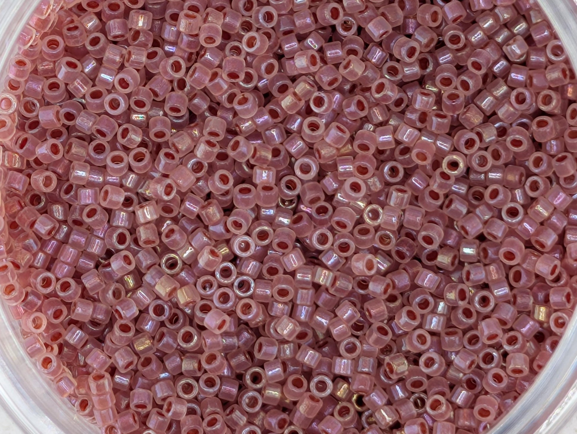 A close-up image of a container filled with numerous small, pink beads.