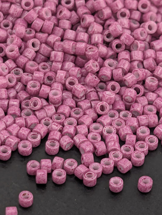 a large pile of small, pink beads scattered on a dark surface.