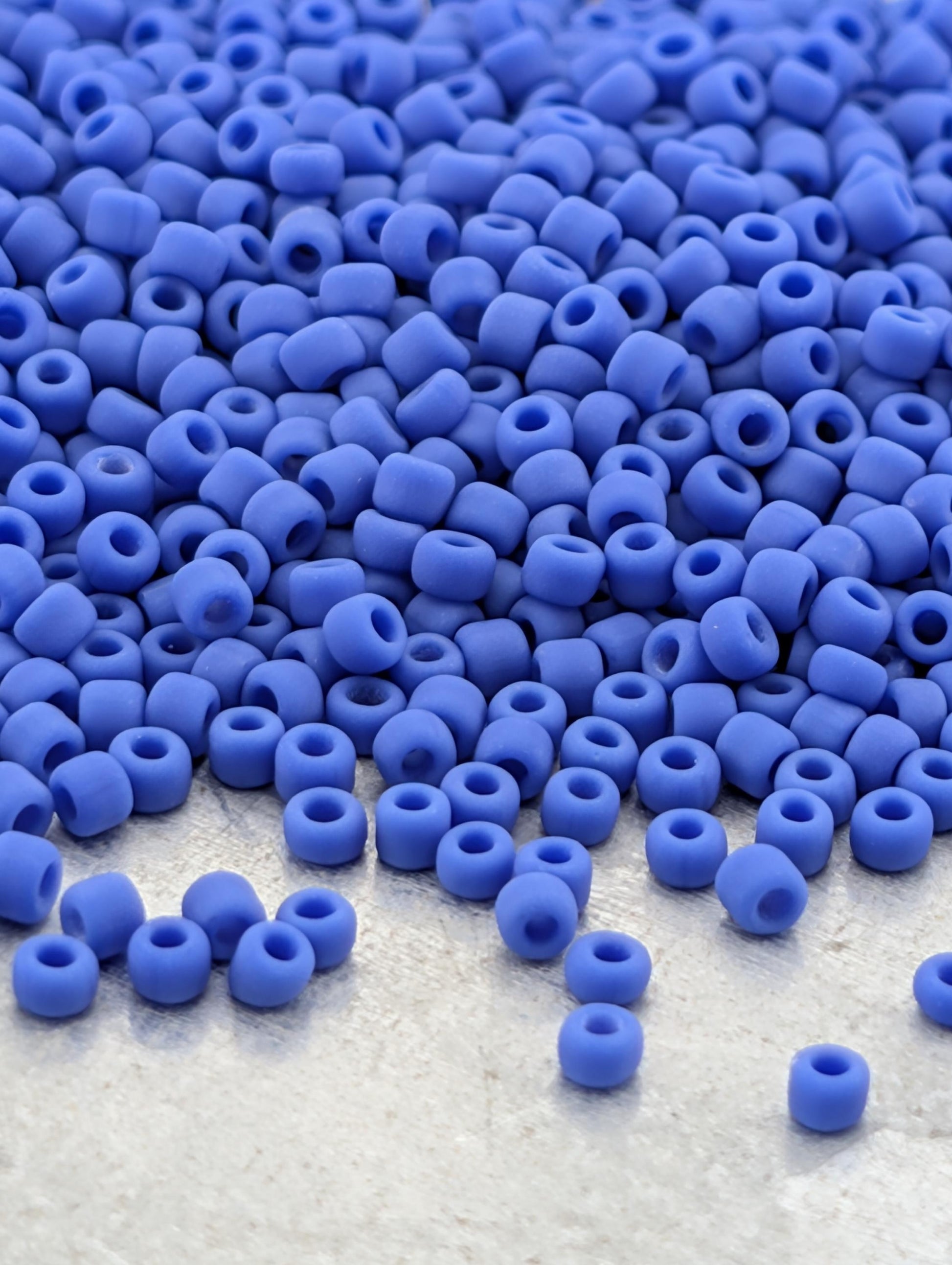 a large pile of blue beads scattered on a white surface.
