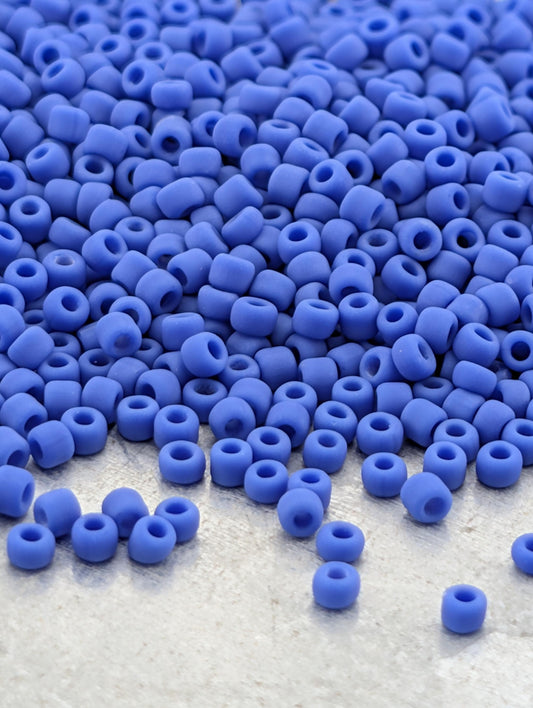 a large pile of blue beads scattered on a white surface.