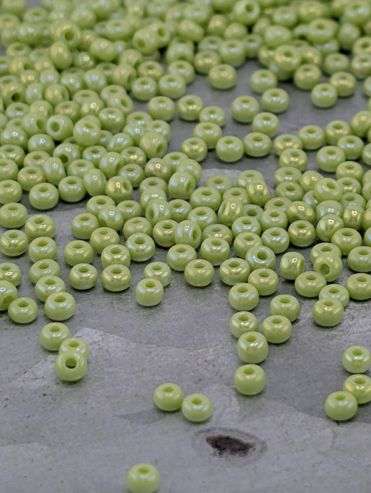 a collection of small, round, green beads scattered on a gray surface.