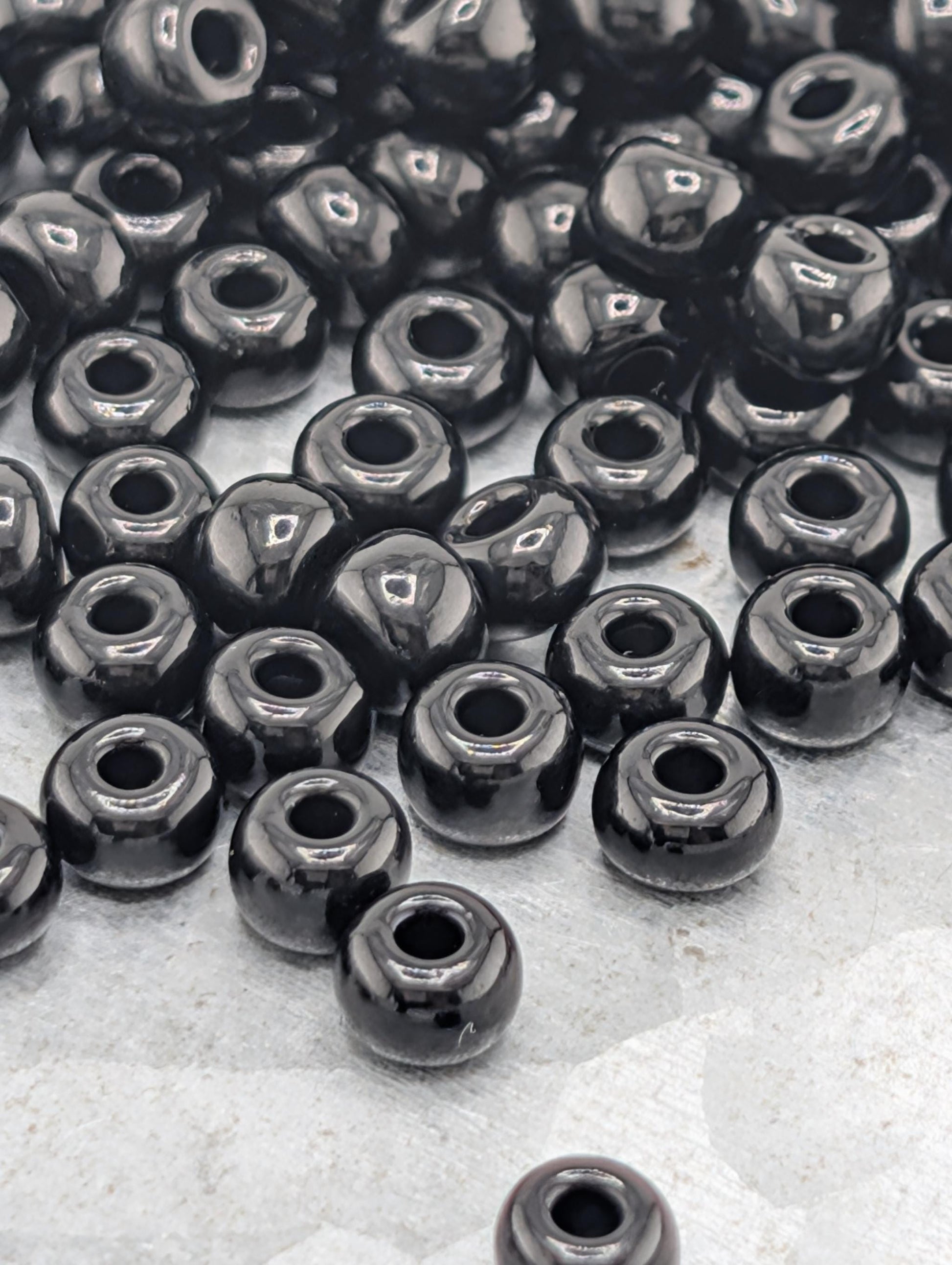 a collection of black beads scattered on a surface, with some of the beads overlapping each other.