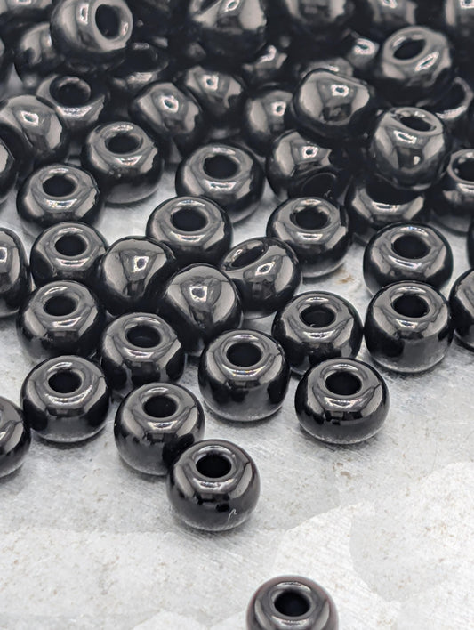 a collection of black beads scattered on a surface, with some of the beads overlapping each other.